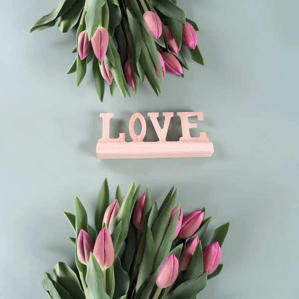 The inscription LOVE and Fresh spring tulip flowers on a green background, banner, spring flowers, pink tulips.