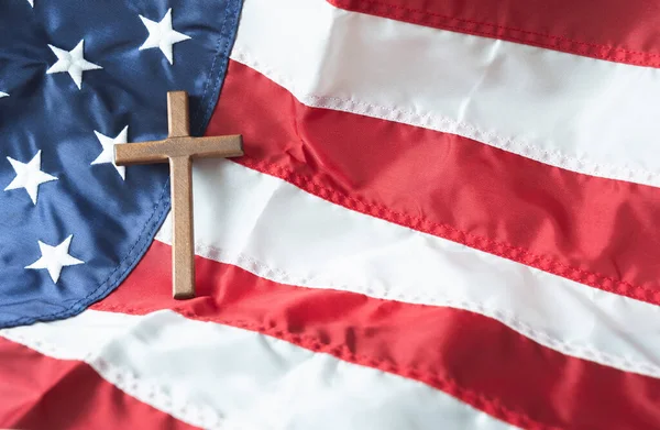 Religious right concept with Christian Wooden cross on American flag background. Copy space.