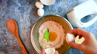 Kırsal mavi masa yerine elektrikli karıştırıcı kullanan bir kadın, un kabında yumurta çırpıyor. Kapat.