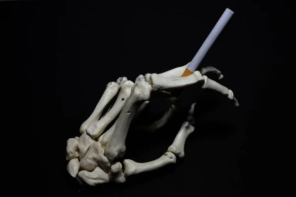 Sigaralı bir iskelet el. Sigarayı bırakmanın sembolü. Sağlıksız alışkanlık.
