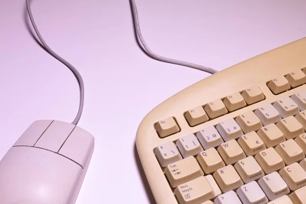 Eski bir bilgisayar klavyesinin ve beyaz arka planda kabloları olan bir farenin üst görüntüsünü aç.
