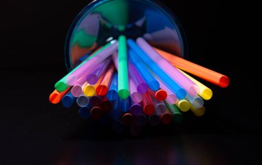 Siyah arka planda renkli plastik pipetlerin yakın görüntüsü. Doku. AB yasağı kavramı.