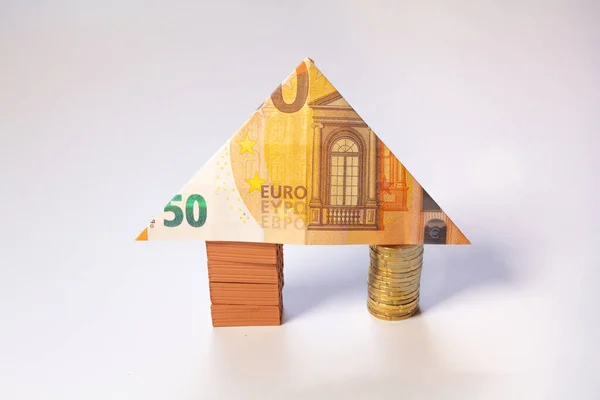 House made of brick and coin stacks with a 50 euro note as a roof. Home loan real estate for mortgage concept.