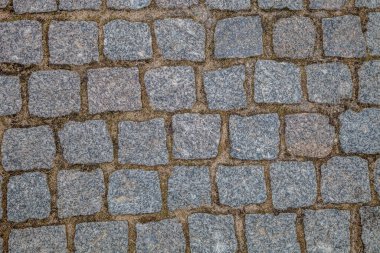 Gri kare taşlı asfalt yol.