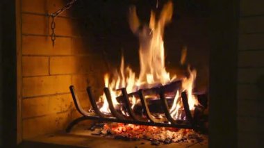 Şöminede ateş yanıyor. El yanan ocağa odun atar ve odunları demirle hareket ettirir. Sıcaklık ve ev konforu. Bir kır evinin şöminesinde ateş açın..
