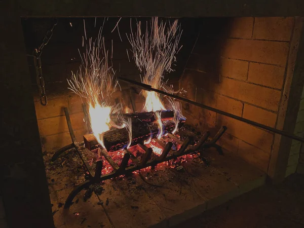 Le feu brûle dans la cheminée. La main jette du bois dans le foyer brûlant et déplace le bois avec un poker. — Photo