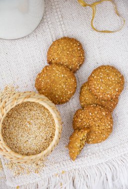 Susamlı kurabiyeler, hasır sepetteki susam tohumları, pürüzlü masa örtüsü.
