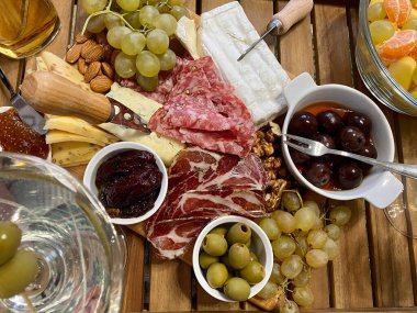 Soğuk et ve çeşitli peynir çeşitleri, zeytin, ahşap bir tahtanın üzerinde salamura üzüm. Şarap çerezi