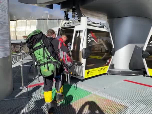 Elbrus Resort, Karachay-Cherkessia, Ryssland, 15 augusti 2020: Två starka män med klätterutrustning kommer in i kabinbanan — Stockvideo