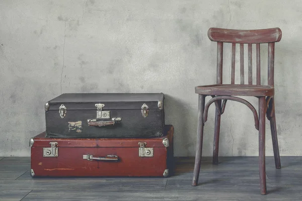 Starý kufr a dřevěné židle — Stock fotografie
