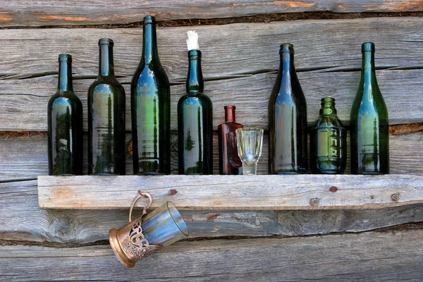 Flaskor, vinglas och glas stå på en hylla — Stockfoto