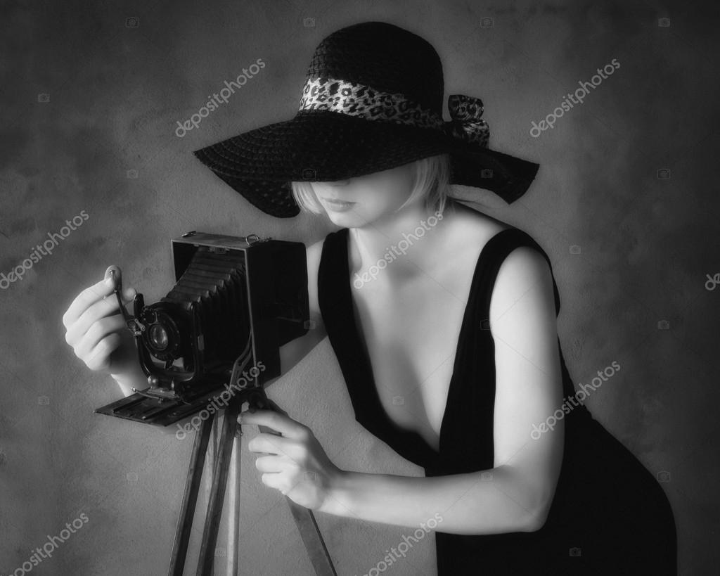 Girl photographer in a black hat with an old camerablack and white image de sergeka