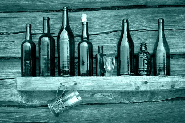 Bottles, wineglass and glass stand on a shelf — Stock Photo, Image