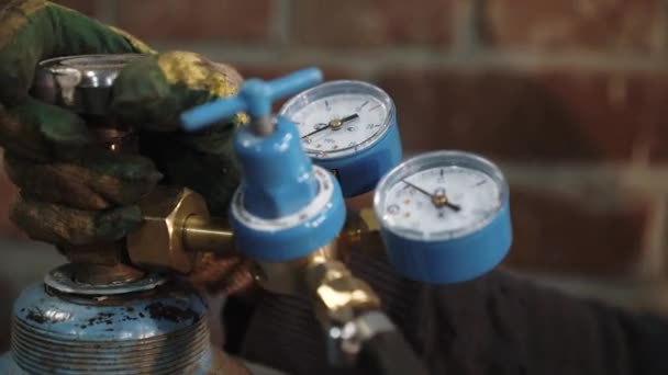 Ciężki pracownik hutnictwa otwiera zawór butli gazowej z ciśnieniomierzem — Wideo stockowe