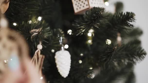 Närbild av kvinnliga händer dekorera julgran med trä snöflinga — Stockvideo