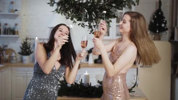 Twee vrouwen in glimmende jurken dansen met de sterretjes en rozenwijn met Kerstmis — Stockvideo