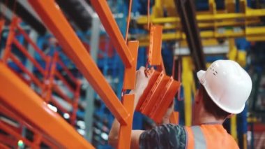 Miğferli bir işçi barut kaplama hattındaki boya parçalarını çıkarıyor.