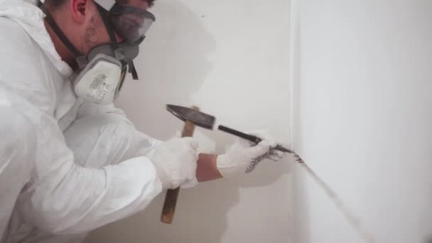 A worker knocks hammer on chisel to hollow out a hole in the wall, medium shot — Stock Video