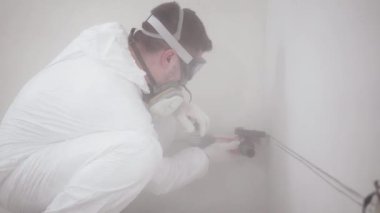 Tulum giymiş bir adamın orta boy fotoğrafı yeni evinde öğütücüyle bir duvarı testereyle kesiyor.