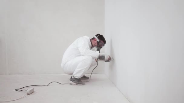 İşçi dairede tamirat yapar, öğütme makinesiyle duvar testeresi yapar, genel plan — Stok video