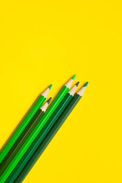 Діагональні зелені гострі дерев'яні олівці на яскраво-жовтому фоні, ізольовані, копіюють простір, сміються — стокове фото