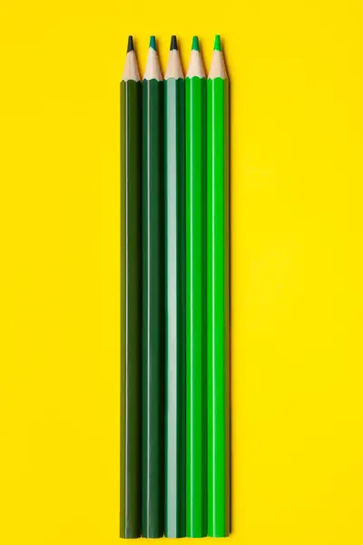 Vertikale grüne scharfe Holzstifte auf leuchtend gelbem Hintergrund, isoliert, Kopierraum, Attrappe — Stockfoto