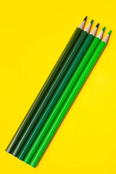 Diagonal green sharp wooden pencils on a bright yellow background, isolated, copy space, mock up — Stock Photo, Image