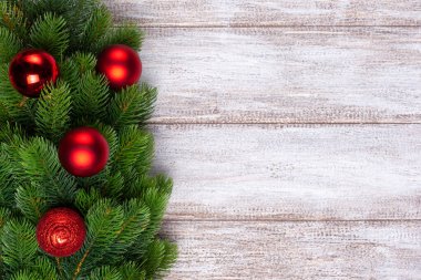 Noel ağacının dallarındaki üç kırmızı top ahşap arka planda, Noel kartı.