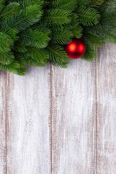 Bola roja en las ramas de un árbol de Navidad sobre un fondo de madera, se burlan — Foto de Stock