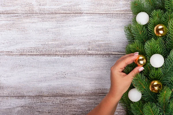 decoration, mock up, a womans hand hangs a Golden ball on the Christmas tree,