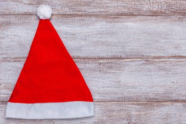Tahta arka planda kırmızı Noel Baba şapkası, Noel kartı.