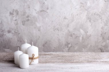 Tahta bir masada, bir halatın içinde dört beyaz mum, Noel kartı.