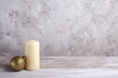 Vanilya mumunun maketi, ahşap bir masada altın bir Noel topu.