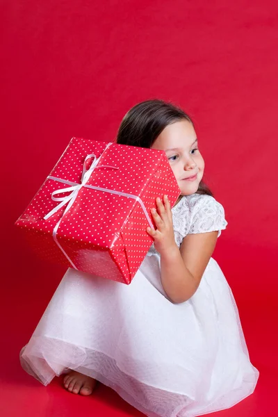 stock image beautiful young lady sitting on the floor and shaking gift near her head, trying to figure out surprise, new year party