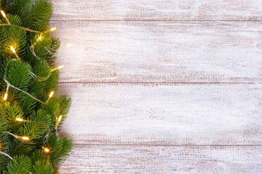 Tahta bir arka planda sarı bir çelenkle süslenmiş bir Noel ağacı modeli, kartpostal.
