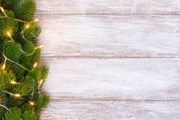 Tahta bir arka planda sarı bir çelenkle süslenmiş bir Noel ağacı modeli, kartpostal.