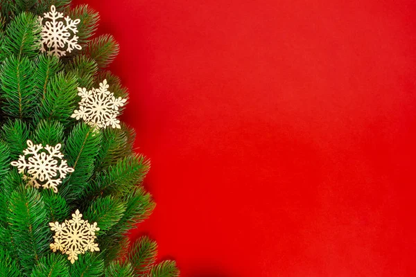 Tarjeta de felicitación de ramas de árbol de Navidad con copos de nieve de madera aislados sobre fondo rojo, se burlan de — Foto de Stock