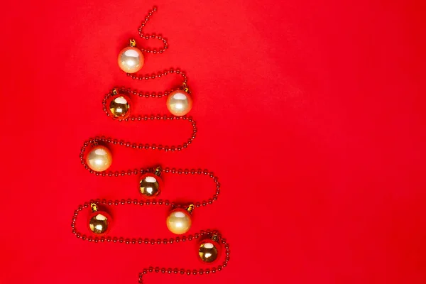 Μακιγιαρισμένο από γιρλάντα από χάντρες σε σχήμα χριστουγεννιάτικου δέντρου με χρυσό καθρέφτη και μπάλες παγωμένες σε κόκκινο φόντο — Φωτογραφία Αρχείου