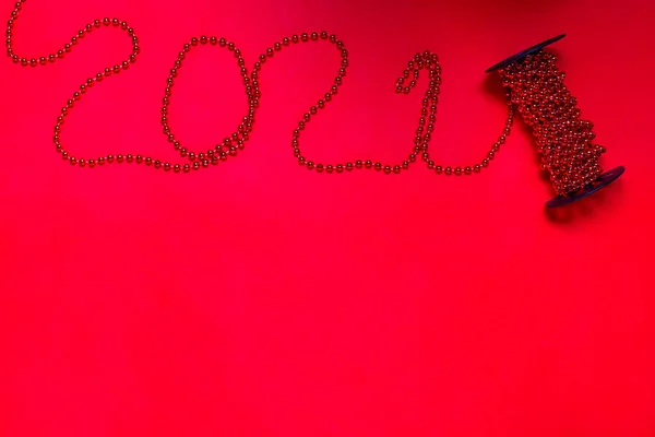 Mock up of garlands of beads on spool for a new year tree in the form of the number 2021 on a red background, copy space — Stock Photo, Image