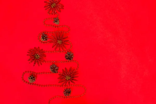 postcard from a garland of beads laid out in the form of a Christmas tree with decorations from cones of brilliant red flowers, isolated on scarlet, mock up