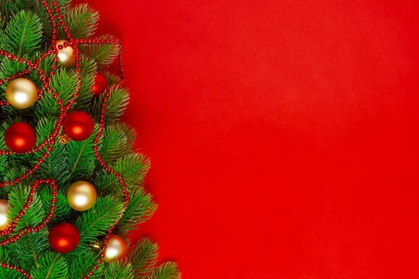 Las ramas del árbol de Navidad tarjeta de felicitación con bolas rojas y doradas, una guirnalda de cuentas sobre un fondo rico, se burlan de — Foto de Stock