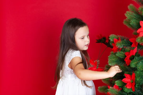 mock up girl in white dress decorates artificial flowers Christmas tree isolated on red background with space for text