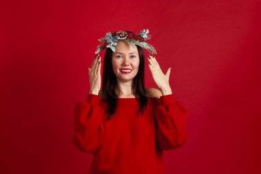 Mutlu gülümseyen Asyalı genç bir kadının portresi gözlerini açıyor ya da kapıyor, kırmızı bir arka planda hediye bekliyor.