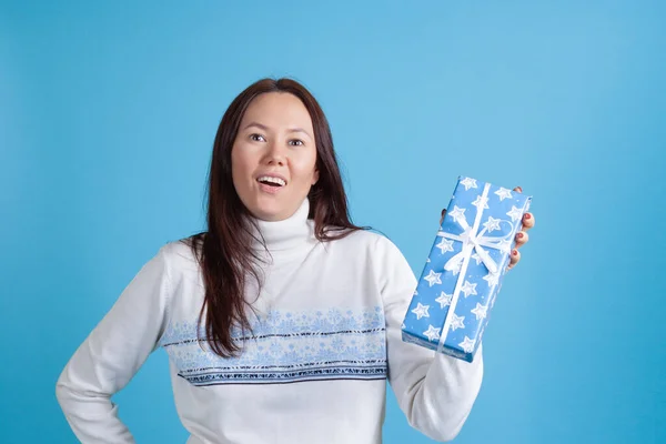 Close-up portret van verrast gelukkig aziatische jonge vrouw in trui ontvangen kerstcadeau, geïsoleerd op azuurblauwe achtergrond — Stockfoto