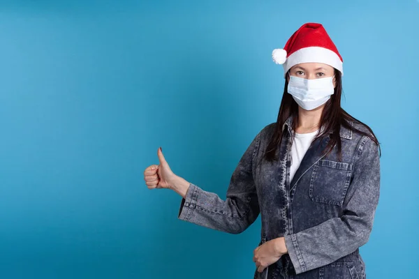 Mujer joven asiática con un sombrero de Santa Claus y una máscara de protección contra el virus médico, protección confiable contra la gripe —  Fotos de Stock