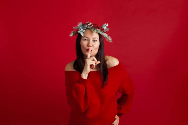 크리스마스 화환에 입을 손가락으로 꼭 다물고 있는 아시아 여성의 사진을 클로즈업 해 주 세요. — 스톡 사진
