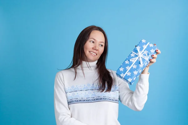 스웨터를 입고 푸른 선물 상자를 보고 있는 한 젊은 아시아 여성의 사진을 클로즈업 한 모습 — 스톡 사진