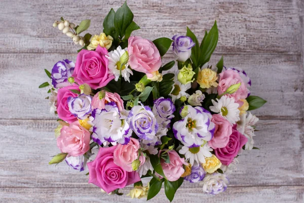 Bouquet plat de roses, marguerites, lisianthus, chrysanthèmes, bourgeons non ouverts sur une table à planches en bois minable — Photo