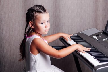 Beyaz bir yaz elbisesi içinde dalgın, hayalperest bir kız ve iki örgülü tren akoru ev içinde elektronik bir sentezleyicide.