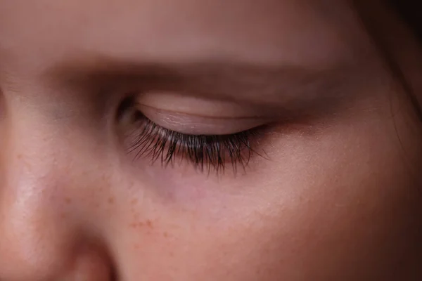 Close-up macro-oog van een blank meisje met lange donkere wimpers en een sombere, droevige blik — Stockfoto